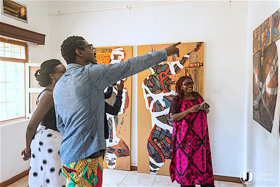 Sekajugo explains one of the paintings to Nyanzi. 