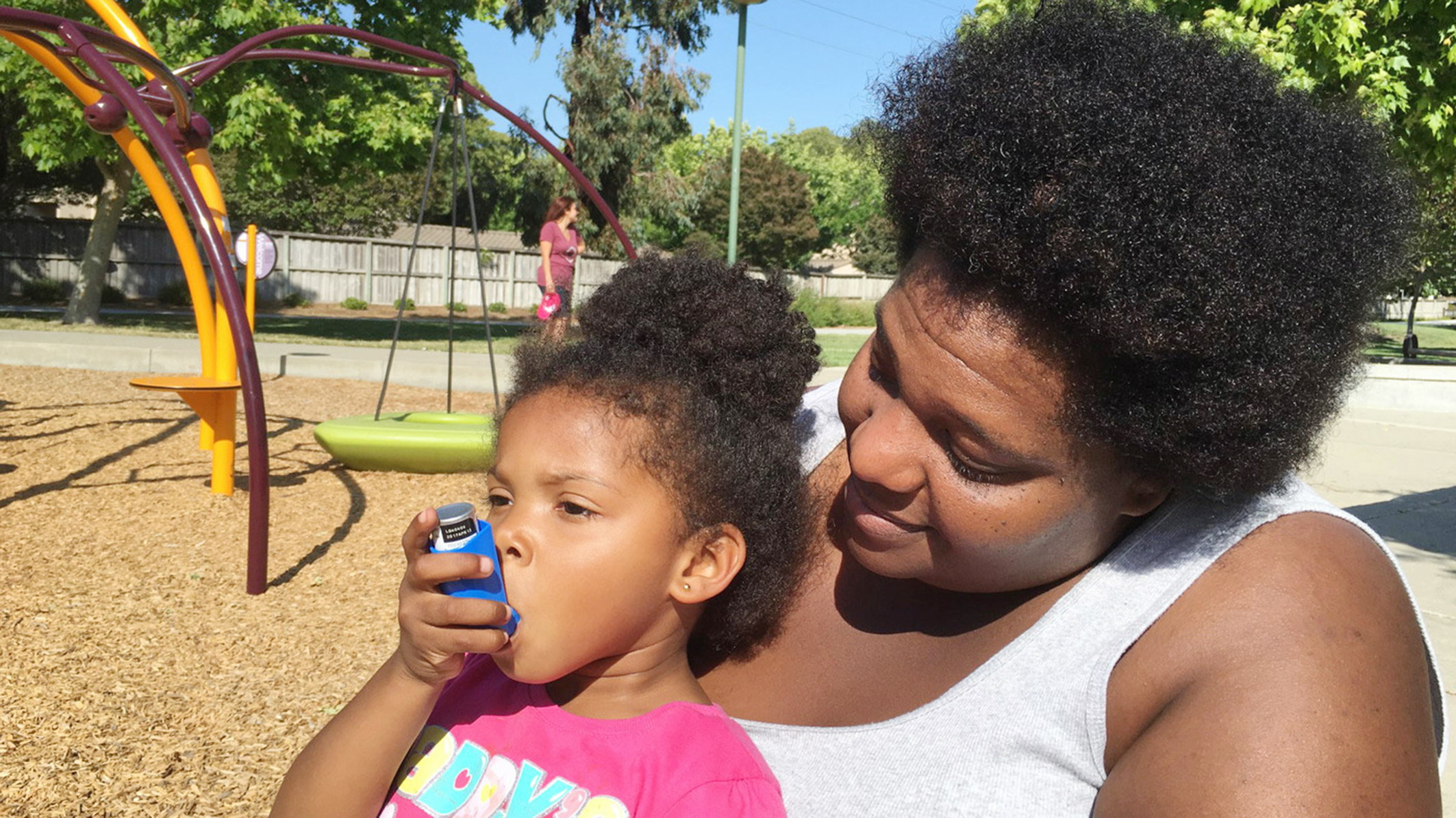Zunika Crenshaw helps her 3-year-old daughter Jhase Crenshaw Bass with an asthma inhaler.