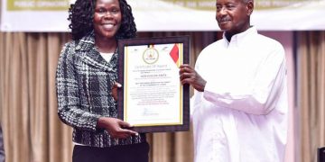 President Yoweri Museveni handing over the best performing minister to Privatisation and Investment Minister Evelyn Anite.