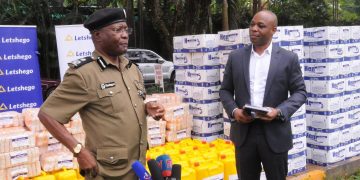AIGP Asan Kasingye applauds Letshego Uganda for their generous offer to the Uganda Police worth $10000 towards the control of COVID-19. Looking on is Letshego CEO Giles Aijukwe.