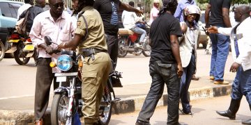The unidentified men in black surrounding a boda boda cyclist after they beat him up and Deputy RPC Kampala south Geoffrey Tayeebwa assisting them to take the boda boda PHOTO BY ABUBAKER LUBOWA