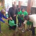 Archbishop Paul Ssemwogerere, joined by Joseph Masembe and young participants, planting a tree at the  archbishop's residence in Rubaga.