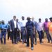 State Minister for Sports, Hon. Peter Ogwang (in a T-shirt and hat), led the contractors, FUFA, and NCS officials on a site visit to Hoima earlier this year.
